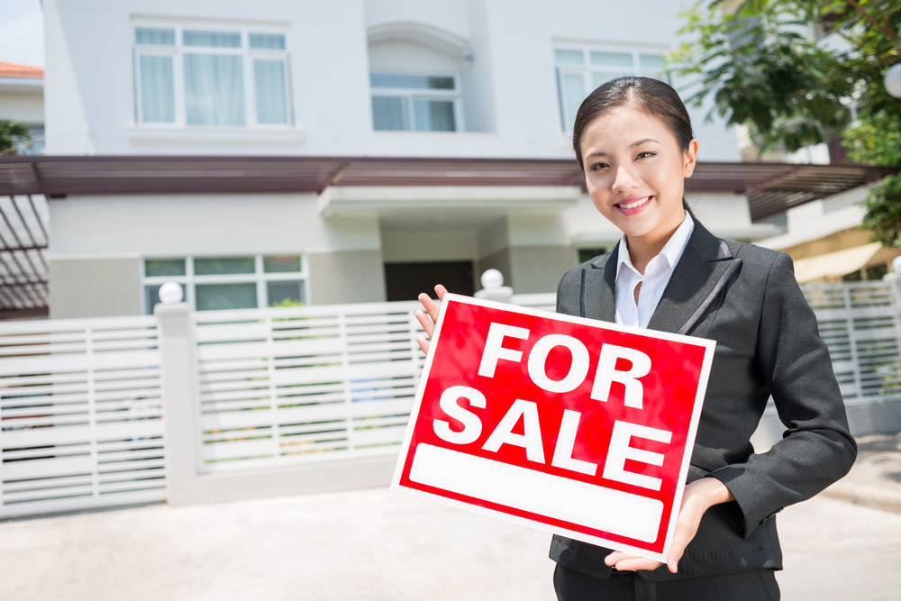 Real estate agent holding a for sale sign Effectively Advertise your Real Estate listings in Display Advertising both Online and in Print
