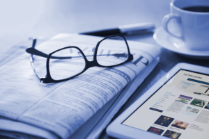 newspaper and tablet on a table with glasses sitting on top Advertising resources
